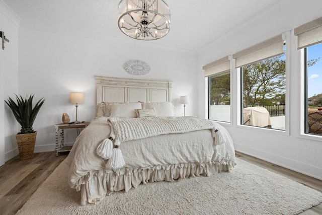 bedroom featuring wood finished floors, a notable chandelier, and baseboards