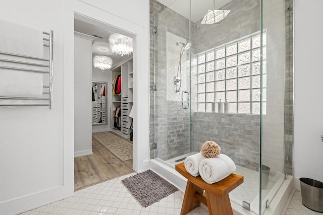 bathroom with a shower stall, a spacious closet, and an inviting chandelier