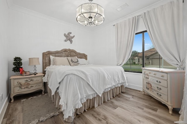 bedroom with a notable chandelier, baseboards, visible vents, and light wood-style flooring