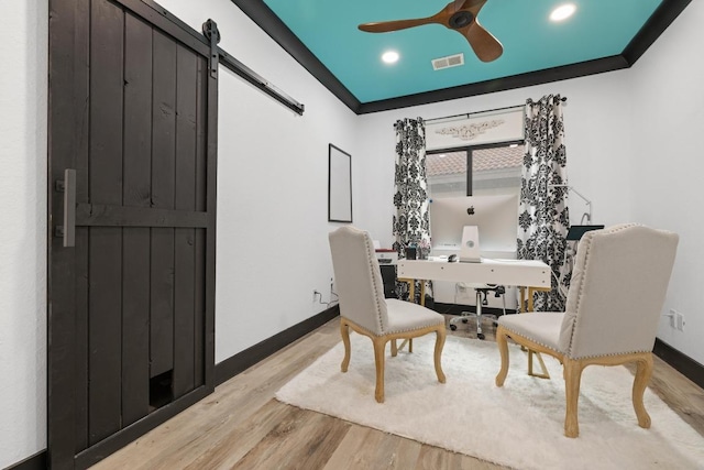 dining space featuring visible vents, baseboards, a barn door, a ceiling fan, and light wood finished floors