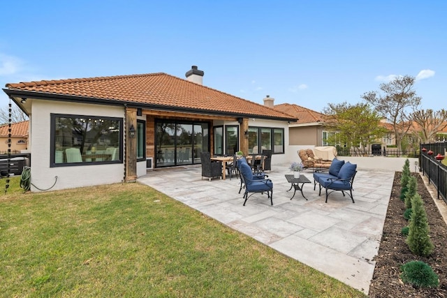 rear view of property with a tiled roof, a patio area, fence private yard, and a lawn