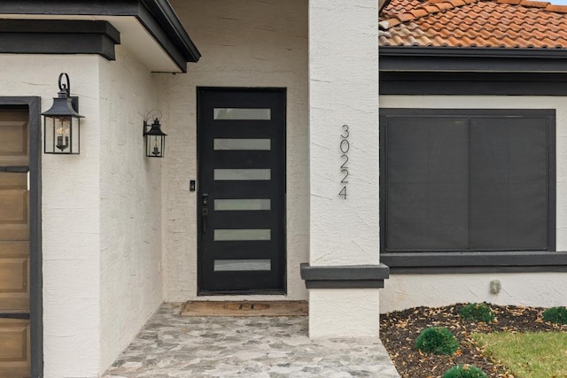 entrance to property featuring stucco siding and a tiled roof