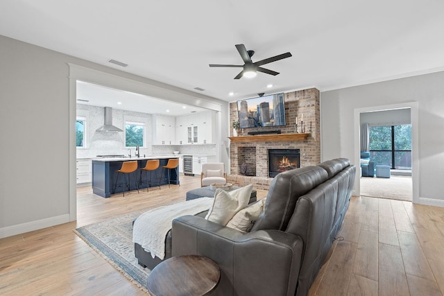 3300 Lost Oasis Holw, Austin, TX 78739 - living room featuring ceiling fan, wine cooler, light wood-style flooring, a fireplace, and baseboards