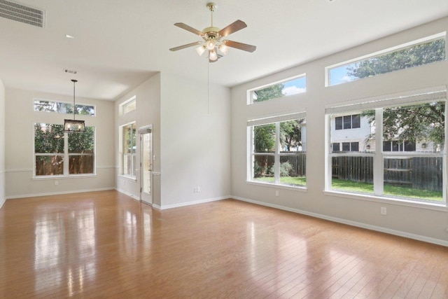 spare room featuring hardwood / wood-style flooring, baseboards, a ceiling fan, and a high ceiling