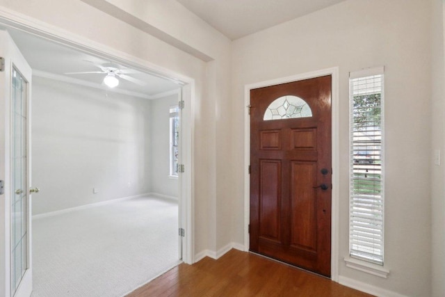 entrance foyer featuring wood finished floors, healthy amount of natural light, baseboards, ceiling fan, and ornamental molding