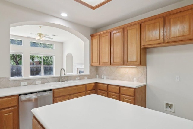 kitchen featuring a sink, dishwasher, light countertops, decorative backsplash, and a ceiling fan