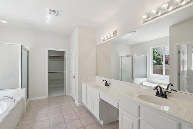 full bath featuring a stall shower, a garden tub, a spacious closet, double vanity, and tile patterned flooring
