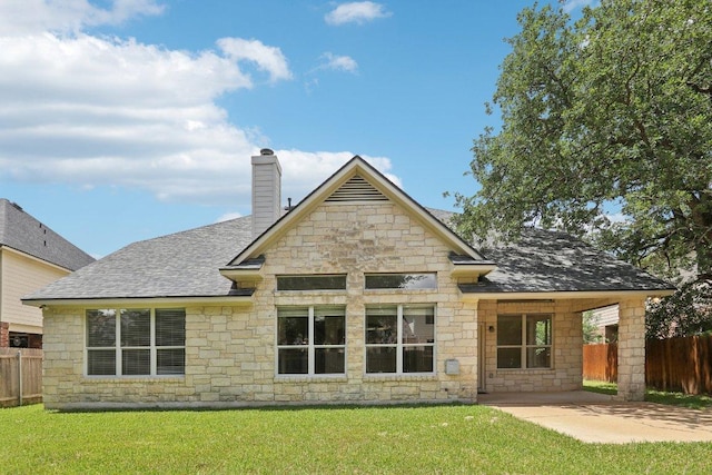 back of property with stone siding, roof with shingles, a chimney, and a patio