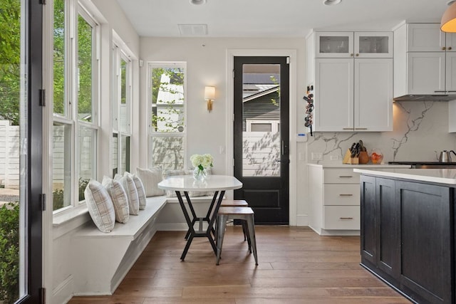 kitchen with wood-type flooring, light countertops, backsplash, and breakfast area
