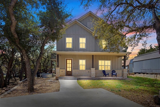 view of front of property featuring covered porch, stone siding, and board and batten siding
