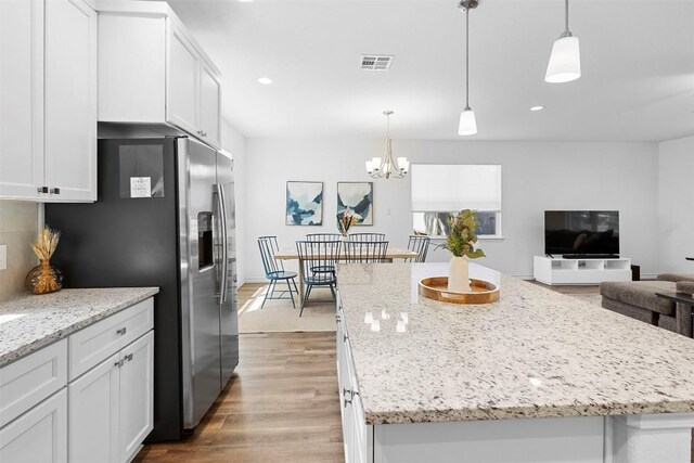 kitchen with white cabinetry, visible vents, light wood-style floors, and a center island