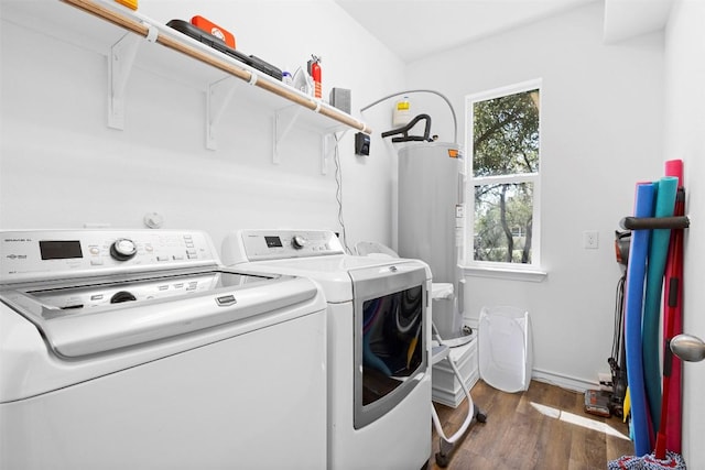 washroom featuring water heater, washing machine and dryer, laundry area, and wood finished floors