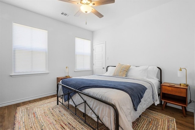 bedroom with baseboards, ceiling fan, visible vents, and wood finished floors