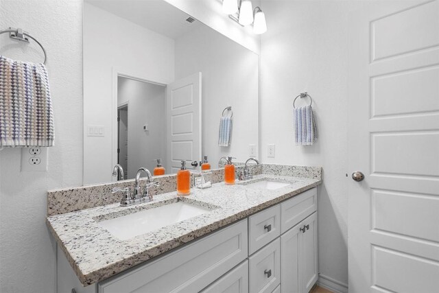 bathroom with double vanity, visible vents, and a sink