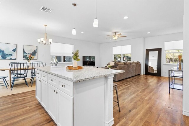 kitchen with light wood-type flooring, hanging light fixtures, a kitchen island, and visible vents