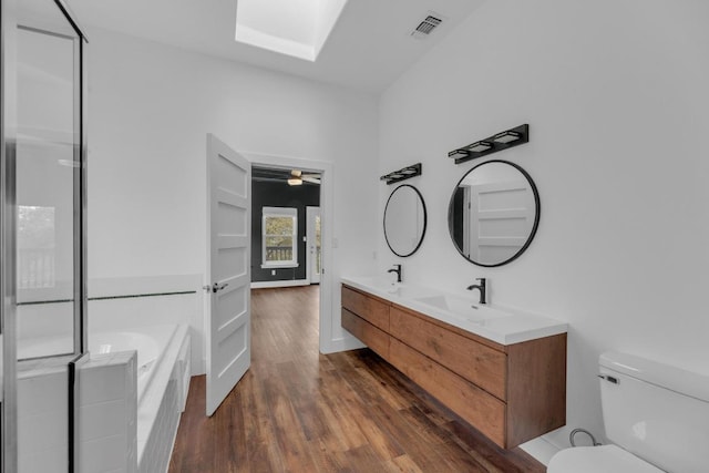 20912 High Dr, Lago Vista, TX 78645 - bathroom with wood finished floors, a bath, double vanity, toilet, and a skylight