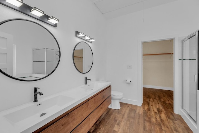 20912 High Dr, Lago Vista, TX 78645 - bathroom with wood finished floors, a shower with shower door, double vanity, toilet, and a walk in closet
