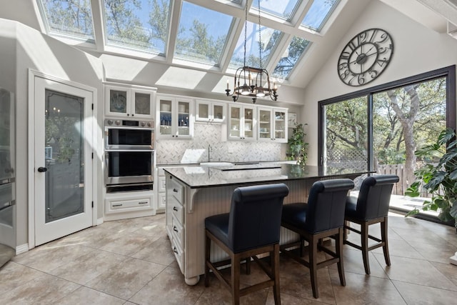 502 Explorer, Lakeway, TX 78734 - kitchen featuring a skylight, light tile patterned flooring, tasteful backsplash, white cabinetry, and high vaulted ceiling
