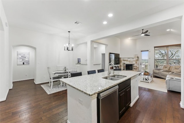 22300 Verbena Pkwy, Spicewood, TX 78669 - kitchen featuring dishwasher, open floor plan, a stone fireplace, dark wood-style flooring, and light stone counters