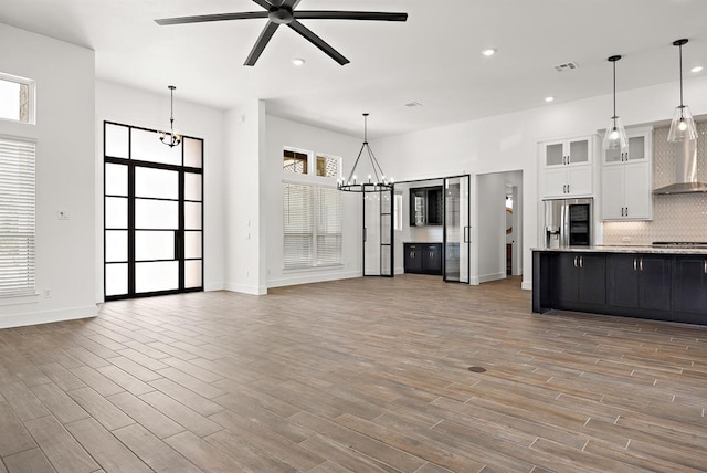 120 NW Strada Luca NW, Florence, TX 76527 - kitchen with stainless steel refrigerator with ice dispenser, wall chimney exhaust hood, a chandelier, white cabinets, and open floor plan
