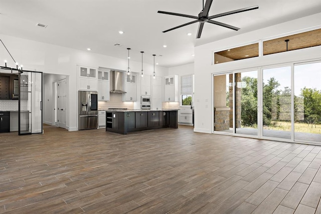 120 NW Strada Luca NW, Florence, TX 76527 - kitchen featuring appliances with stainless steel finishes, open floor plan, wall chimney range hood, white cabinetry, and recessed lighting