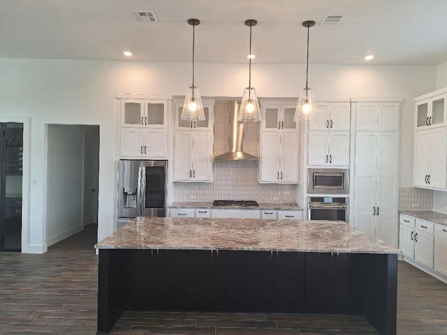 120 NW Strada Luca NW, Florence, TX 76527 - kitchen featuring wall chimney range hood, stainless steel appliances, dark wood-style floors, white cabinets, and tasteful backsplash