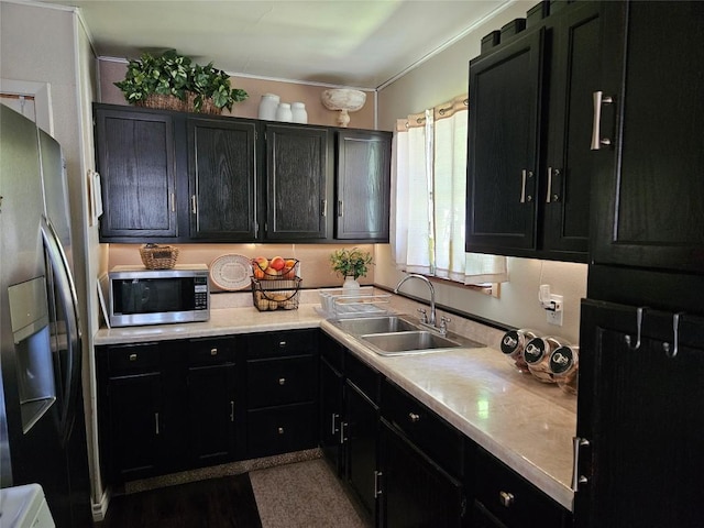 kitchen featuring a sink, dark cabinets, light countertops, and stainless steel appliances
