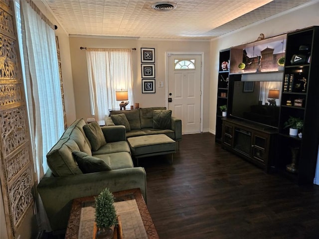living room with visible vents, crown molding, and wood finished floors