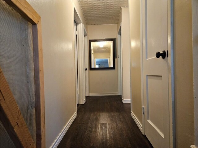corridor featuring dark wood-style flooring and baseboards