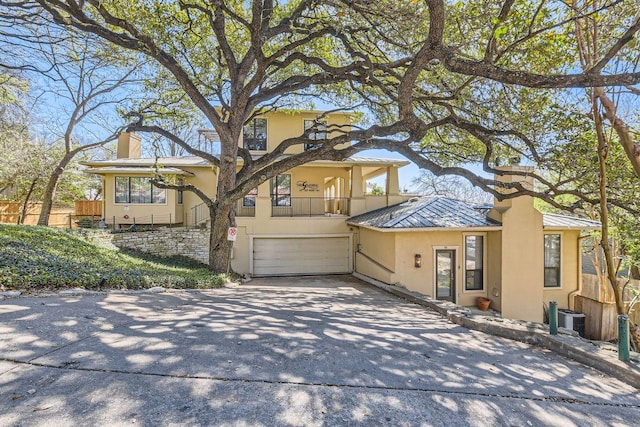 1115 W 7th St W Unit 202, Austin, TX 78703 - view of front of home featuring a chimney, stucco siding, a standing seam roof, concrete driveway, and a balcony