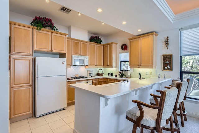 1115 W 7th St W Unit 202, Austin, TX 78703 - kitchen with white appliances, light countertops, a peninsula, a breakfast bar area, and decorative backsplash