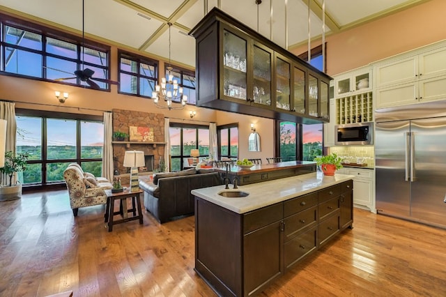 8700 Crest View Rd, Austin, TX 78737 - kitchen with built in appliances, a towering ceiling, dark brown cabinets, wood finished floors, and light countertops