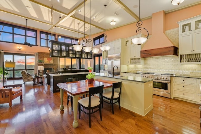 8700 Crest View Rd, Austin, TX 78737 - kitchen featuring high quality appliances, a center island with sink, custom range hood, dark countertops, and dark wood-type flooring