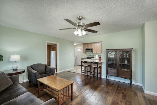 818 Kimbro St, Taylor, TX 76574 - living area featuring a ceiling fan, dark wood finished floors, and a textured ceiling