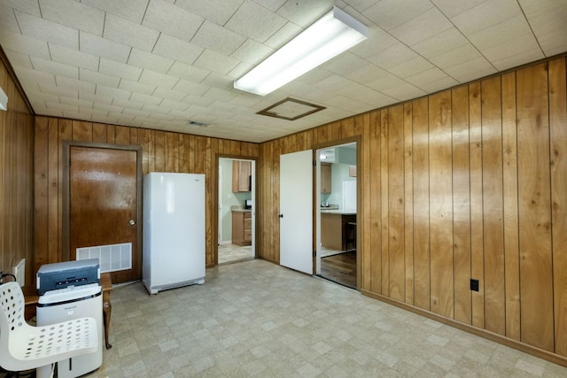 818 Kimbro St, Taylor, TX 76574 - unfurnished bedroom with freestanding refrigerator, light floors, wooden walls, and ensuite bath