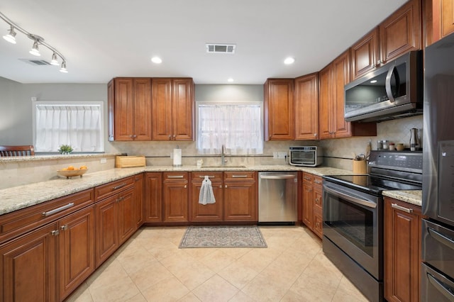 20807 Boggy Ford Rd, Lago Vista, TX 78645 - kitchen featuring appliances with stainless steel finishes, plenty of natural light, tasteful backsplash, brown cabinets, and recessed lighting