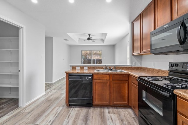 132 Grazing Horse Ln, Manchaca, TX 78652 - kitchen with a tray ceiling, a sink, light wood-type flooring, black appliances, and ceiling fan