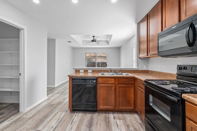 132 Grazing Horse Ln, Manchaca, TX 78652 - kitchen with black appliances, light wood-style floors, a ceiling fan, a peninsula, and brown cabinetry