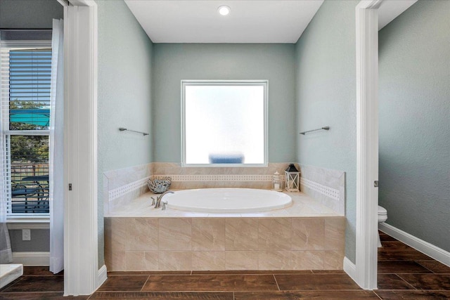 full bath with toilet, a garden tub, and wood tiled floors