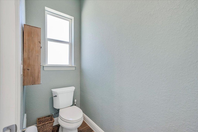 bathroom featuring toilet, baseboards, and wood finished floors