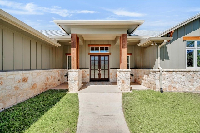 entrance to property with french doors, board and batten siding, metal roof, and a yard