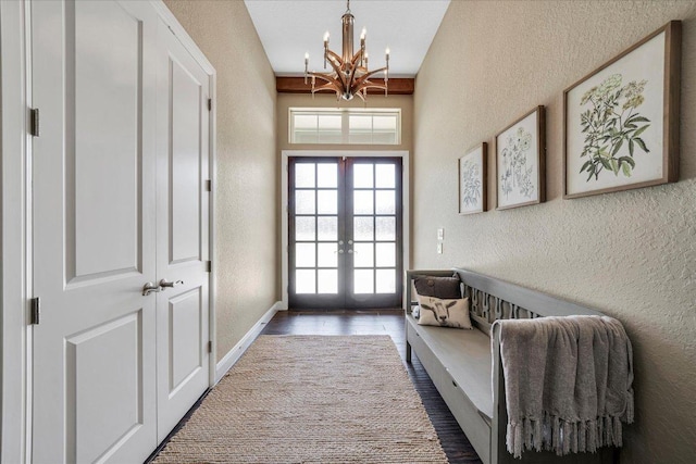 entryway with a textured wall, french doors, a chandelier, baseboards, and wood finished floors