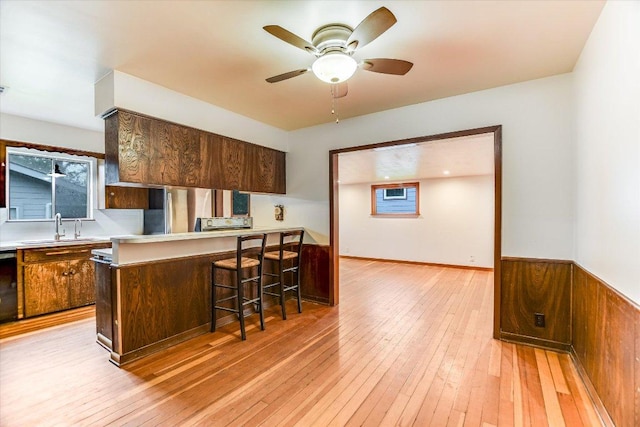 100 E Lisa Dr, Austin, TX 78752 - kitchen with ceiling fan, light countertops, light wood finished floors, and a kitchen bar