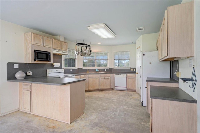 182 Lake Front Dr, Cedar Creek, TX 78612 - kitchen featuring white appliances, light brown cabinetry, dark countertops, under cabinet range hood, and a peninsula