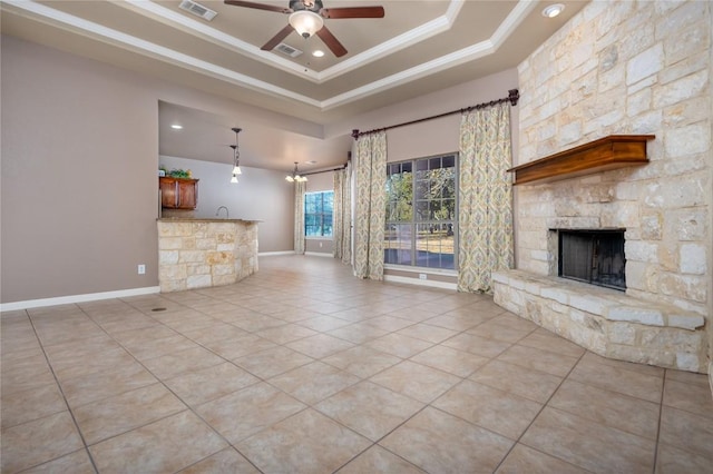 455 Rose Blossom Loop, La Vernia, TX 78121 - unfurnished living room featuring a tray ceiling, light tile patterned floors, a stone fireplace, a ceiling fan, and ornamental molding