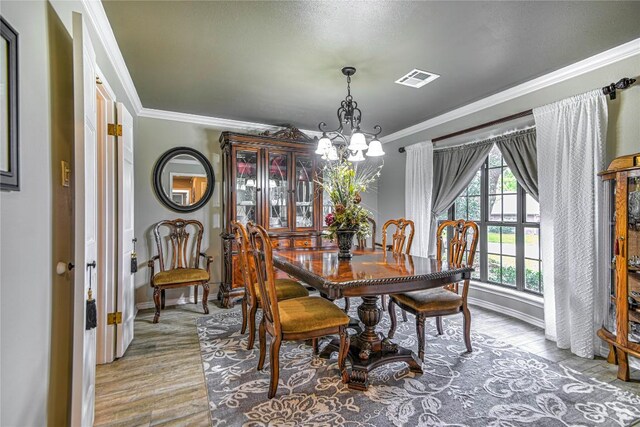 2921 Olympia Dr, Temple, TX 76502 - dining space featuring visible vents, ornamental molding, wood finished floors, and an inviting chandelier