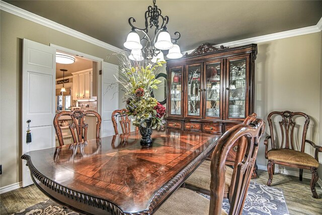 2921 Olympia Dr, Temple, TX 76502 - dining area with ornamental molding, a notable chandelier, baseboards, and wood finished floors