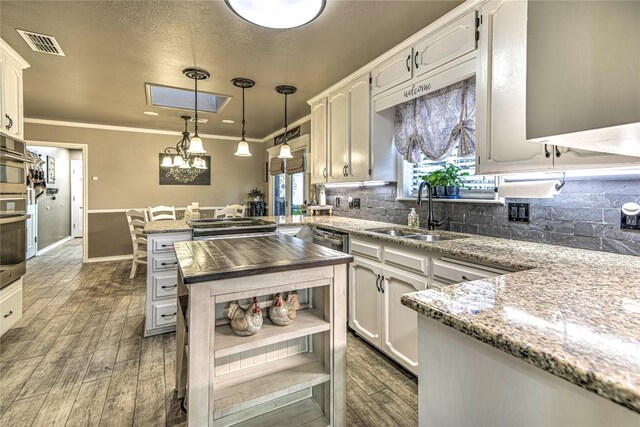 2921 Olympia Dr, Temple, TX 76502 - kitchen featuring visible vents, a peninsula, tasteful backsplash, a sink, and wood tiled floor