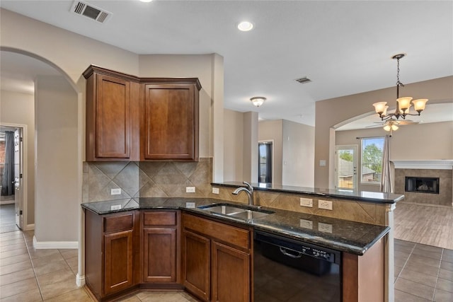 1628 Hidden Springs Path, Round Rock, TX 78665 - kitchen with dishwasher, arched walkways, a sink, open floor plan, and dark stone counters