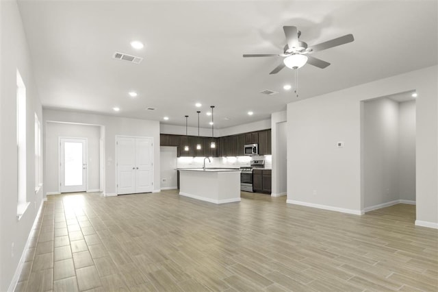 18309 Emu Ln, Manor, TX 78653 - unfurnished living room featuring light wood-style floors, baseboards, a ceiling fan, and recessed lighting
